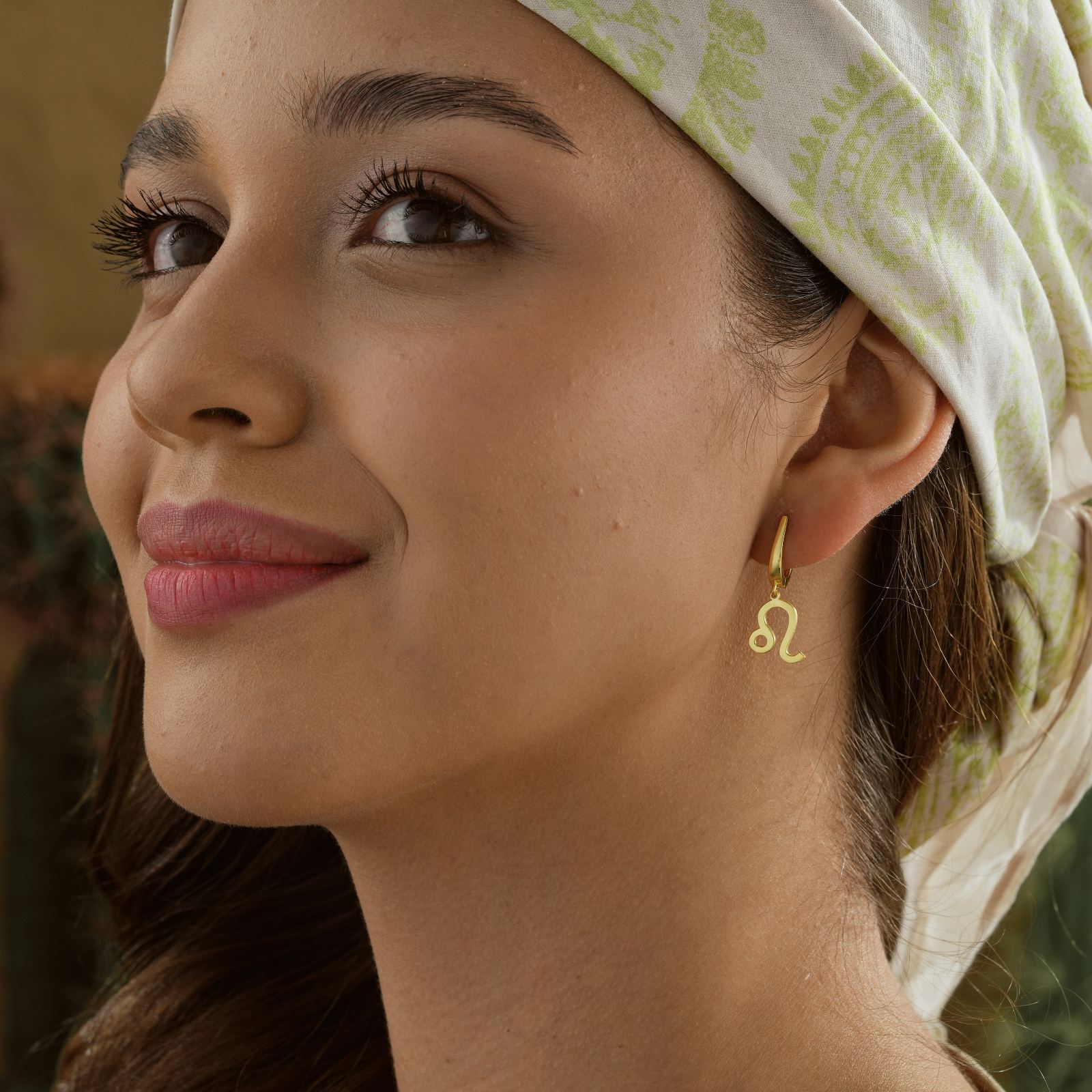 Close-up of a woman wearing Personalized Zodiac Earrings Sterling Silver with a Leo design.